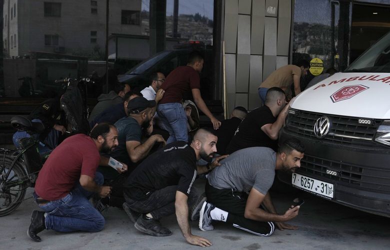Palestinians take cover during fighting between Israeli forces and Palestinian militants outside of a hospital in the West Bank city of Jenin, Monday, June 19, 2023. Israeli helicopter gunships struck targets in the West Bank, during a fierce gunbattle in which Palestinian militants detonated a roadside bomb next to an Israeli military vehicle. Several Palestinians, including a 15-year-old boy, were killed. Dozens of Palestinians were wounded and the Israeli military said seven members of the border police and the army were hurt. They said troops came under fire during an arrest raid in Jenin and shot back at gunmen.  (AP Photo/Majdi Mohammed) XMA112 XMA112