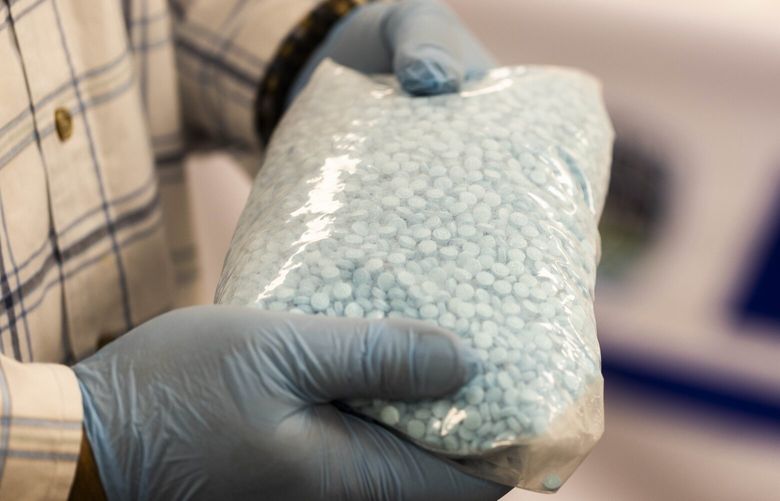 HOLD FOR FENTANYL PROJECT – ASK AN EDITOR
A detective holds up 11,000 fentanyl pills — about $55,000 of drugs — from a drug bust from earlier in the week at the King County Sheriff’s Southwest Precinct on Thursday, Dec. 22, 2022.