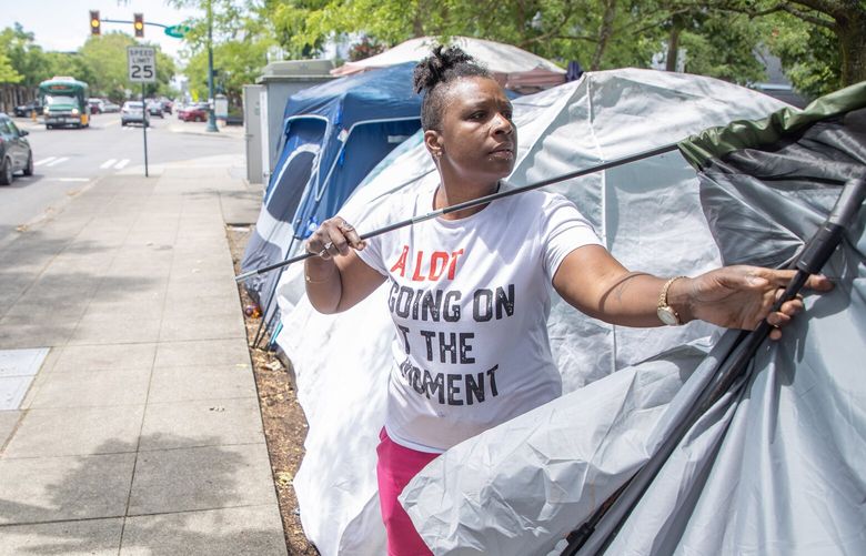 Quita, 39, pitches her tent in downtown Burien Wednesday, June 21, 2023, in Burien.