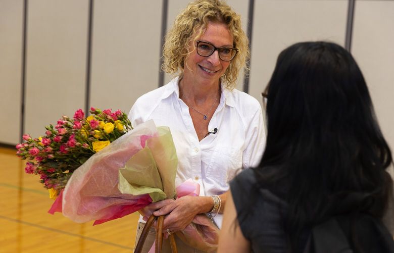 Lori Carpenter, left, who lost her son Garrett to fentanyl poisoning in 2018 just before high school graduation, holds flowers given to her after speaking to a packed student assembly at Shorecrest High School, Monday, June 5, 2023 in Shoreline. Carpenter is thanked by a senior at the conclusion of the event.