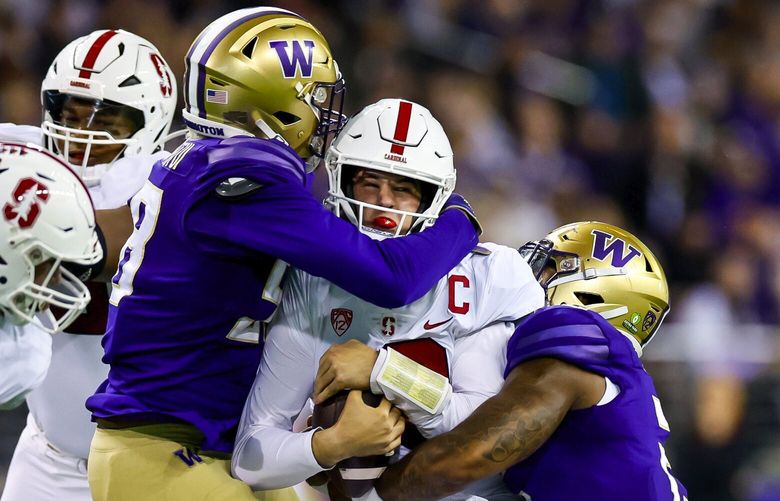 Washington Huskies defensive lineman Zion Tupuola-Fetui, left, and linebacker Cam Bright combine to sack down Stanford Cardinal quarterback Tanner McKee during the first quarter, Saturday, Sept. 24, 2022, in Seattle. 221629