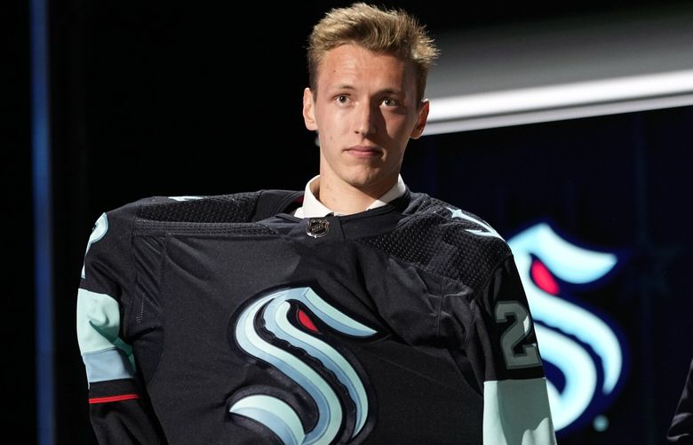 Eduard Sale puts on a Seattle Kraken jersey after being picked by the team during the first round of the NHL hockey draft Wednesday, June 28, 2023, in Nashville, Tenn. (AP Photo/George Walker IV) TNGW155 TNGW155