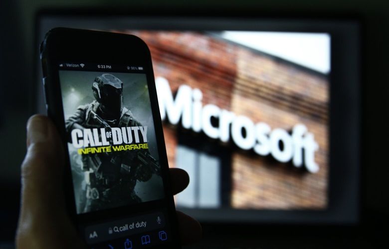 An image from Activision’s Call of Duty is shown on a smartphone near a photograph of the Microsoft logo in this photo taken in New York, Thursday, June 15, 2023. Microsoft CEO Satya Nadella is due in court Wednesday, June 28, to defend the company’s proposed $69 billion takeover of video game maker Activision Blizzard against an attempt by federal regulators to block the deal. Microsoft, maker of the Xbox console, has hailed the deal with Activision Blizzard as a way to make popular Activision games such as Call of Duty more widely available. (AP Photo/Peter Morgan) NYPM310 NYPM310