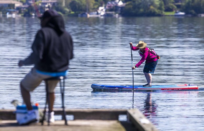 A paddle boarder rides the waters near Stan Sayres Memorial Park & Boat Launch in Seattle on May 10, 2023.
