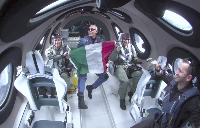 This Thursday, June 29, 2023, image provided by Virgin Galactic shows Italian Air Force Col. Walter Villadei holding up an Italian flag as he and other Italian researchers experience a few moments of weightlessness aboard Virgin Galactic’s rocket-powered spaceplane before gliding back down to Spaceport America in southern New Mexico. With the research flight complete, Virgin Galactic plans to begin commercial flights with paying ticket holders in August. (Virgin Galactic via AP) NYHO402 NYHO402