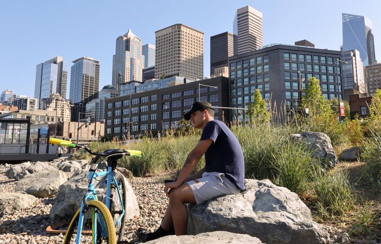 Ehab Anas, from Bermerton, relaxes while waiting for his wife pick him up at the Pioneer Square Habitat Beach in Seattle, on Saturday, July 1, 2023. Anas had just finished his night shift and his ferry was cancelled. “Its gorgeous out here.” he said. Between Colman Dock and Pier 48, a new habitat beach supports the waterfront ecosystem, including enhancing the salmon corridor by adding rocks and nearshore vegetation.