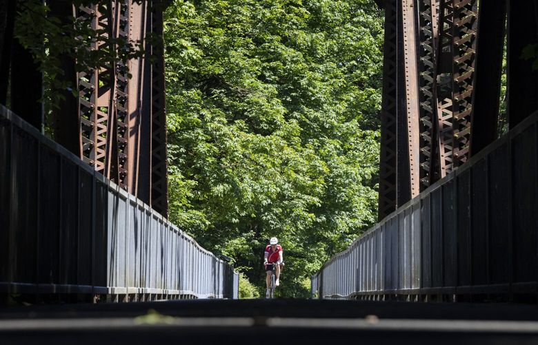 Under sunny skies,  a bicyclist cruises along on the Cedar River Trail near Maplewood Roadside Park in Renton Wednesday, June 28, 2023.  Temperatures are predicted to be in the 70’s until next Monday and then in the 80’s for the rest of next week. 224286

LO