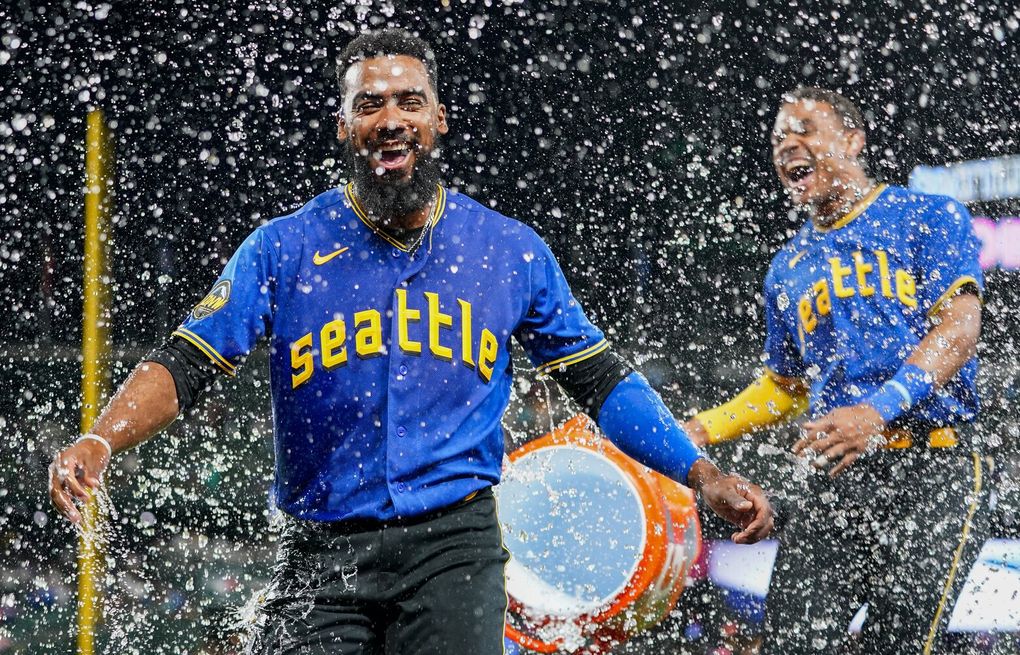 Seattle Mariners' Teoscar Hernandez in the dugout holding the