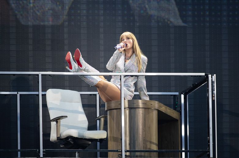 Taylor Swift puts her feet up Saturday evening at Lumen Field. (Luke Johnson / The Seattle Times)