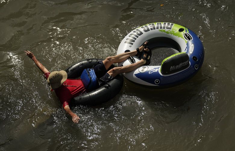 FILE – A tuber floats on the Comal River, July 26, 2023, in New Braunfels, Texas, as the area continues to feel the effects of triple-digit temperatures. Nearly 60% of the U.S. population, are under a heat advisory or flood warning or watch as the high temperatures spread and new areas are told to expect severe storms. (AP Photo/Eric Gay, File) CLI303 CLI303