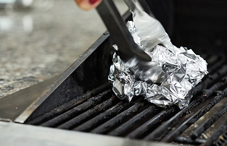 One method of scrubbing the grill is with a ball of crumpled foil (about the size of a navel orange) held in a pair of long-handled tongs. (Tom McCorkle/The Washington Post)