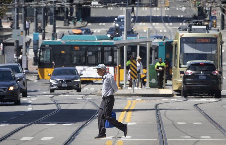 A man crosses S. Jackson St. at 6th Ave. S. In front of the Japantown streetcar station in Seattle Thursday, August 3, 2023.

 Seattleites exposure to heat has grown with increased concretization and diminishing green cover with greater impacts on vulnerable communities. 224626