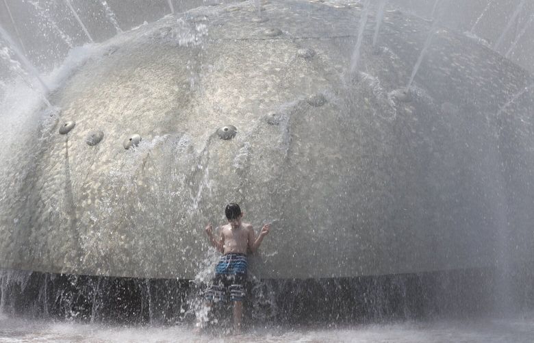A boy cools off at the International Fountain at Seattle Center Wednesday, July 27, 2022.  Wednesday’s high is predicted at 89 degrees, and low 90’s are forecast for the rest of the week. 221103