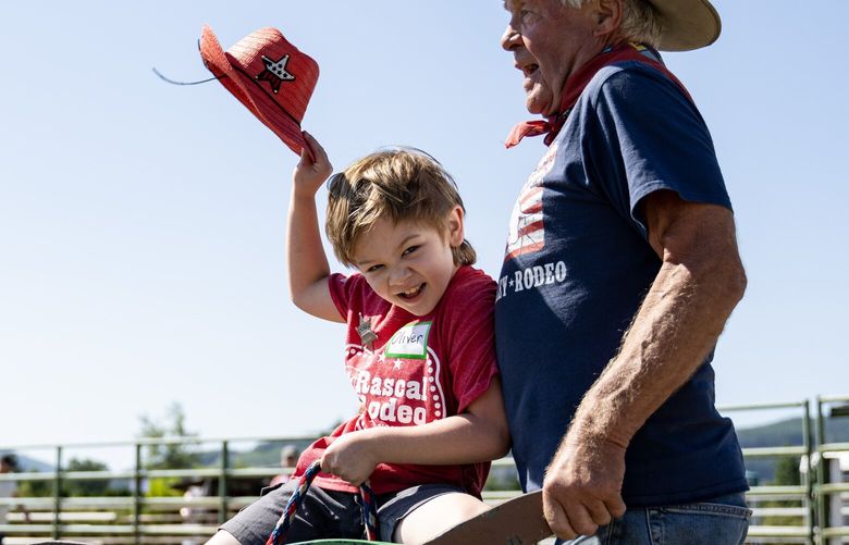 Ciara Jay films her nephew Oliver Gilbert, 6, riding a barrel bull with the help of Jon Schmidt Monday, July 3, 2023, during the Rascal Rodeo at the rodeo grounds in Sedro-Wooley, Wash.