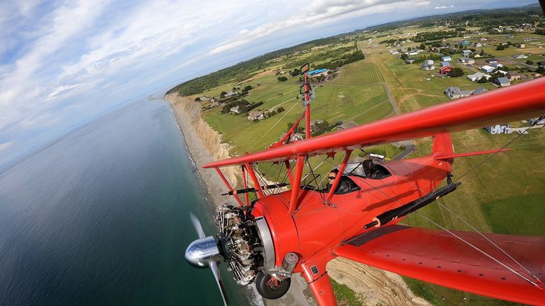 Jason Mayes rides in the front of a Stearman 450 biplane piloted by Mike Mason, back, during a wing walking flight near Sequim in July 2021. (Courtesy of Mason Wing Walking)