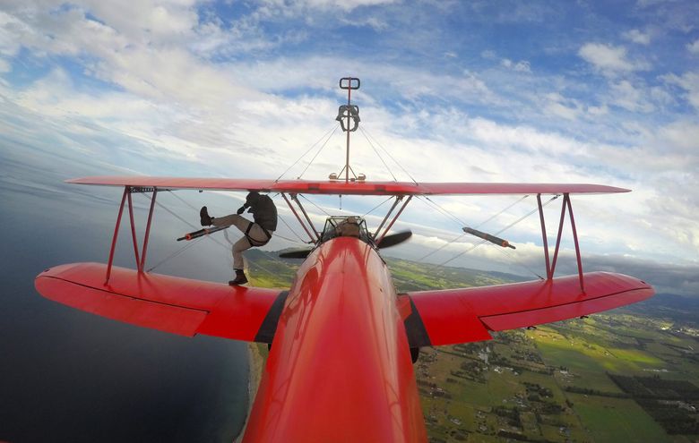 Jason Mayes climbs out of the cockpit of a Stearman 450 biplane piloted by Mike Mason to do an inflight wing walk near Sequim in July 2021. (Courtesy of Mason Wing Walking)