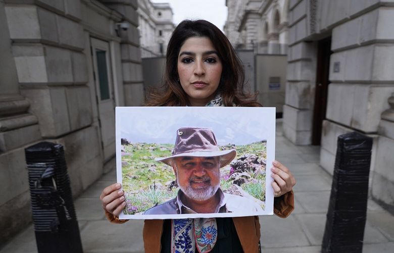 FILE – Roxanne Tahbaz holds a picture of her father Morad Tahbaz who is jailed in Iran, during a protest outside the Foreign, Commonwealth and Development Office in London, April 13, 2022. Iran has transferred five Iranian-Americans from prison, identifying three of the prisoners as Siamak Namazi, Emad Shargi, and Morad Tahbaz, to house arrest. The move comes after Tehran has spent months suggesting a prisoner swap with Washington. (Stefan Rousseau/PA via AP, File) XKS201 XKS201