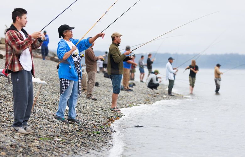 Chante Cole, wearing blue, fishes for pink salmon at Lincoln Park in West Seattle Monday, Aug. 7, 2023. Cole says there is a camaraderie among fishermen, and that the group wants each other to succeed in landing fish. 
 224650