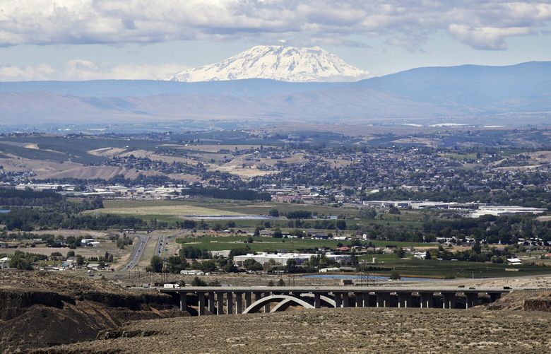 Mount Adams rises in the distance beyond the the Yakima Valley, in Yakima, Wash., June 17, 2020. The coronavirus pandemic is hitting Yakima County hard, with cases surging far faster in than in the rest of the state. The virus has caused turmoil in the farm and food processing industries, where some fearful workers staged wildcat strikes recently to demand that employers provide safer working conditions. (AP Photo/Elaine Thompson) WAET204
