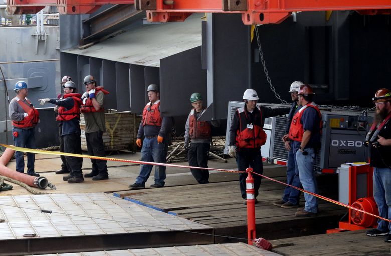 Workers prepare for the superstructure of the ferry Suquamish to move from a barge onto the ferry&#8217;s hull at Vigor Shipyards at Harbor Island. (Alan Berner / The Seattle Times, 2017)