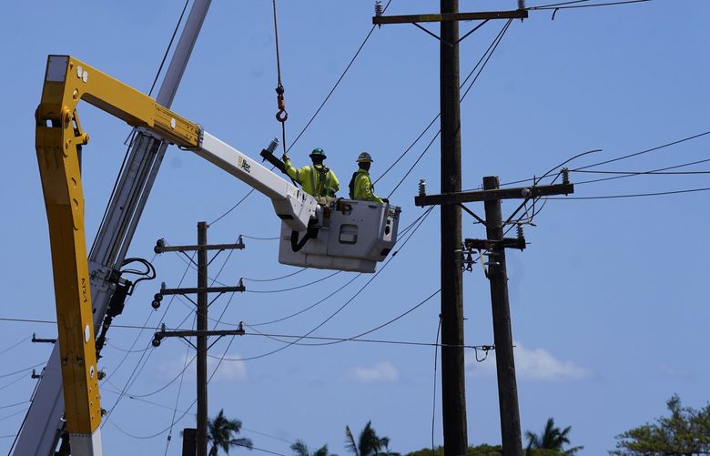 FILE – Linemen work on poles, Sunday, Aug. 13, 2023, in Lahaina, Hawaii, following a deadly wildfire that caused heavy damage days earlier. Hawaiian Electric Co. faces criticism for not shutting off the power amid high wind warnings and keeping it on even as dozens of poles began to topple. (AP Photo/Rick Bowmer, File) NY312 NY312