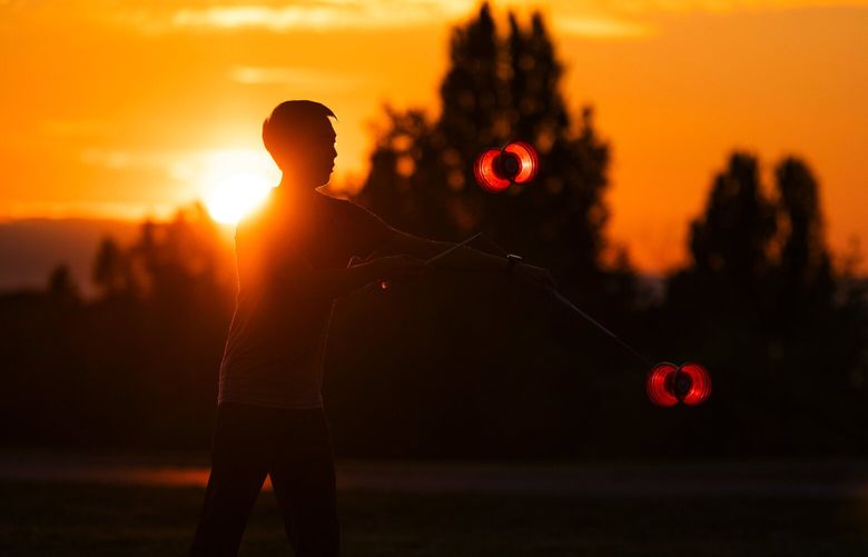 Victor Lin and colleagues from Chinese Yo-Yo performing group, Apex Diabolo (not pictured), practice together as the sun sets during the summer solstice in Jefferson Park in Seattle on July 21, 2023.