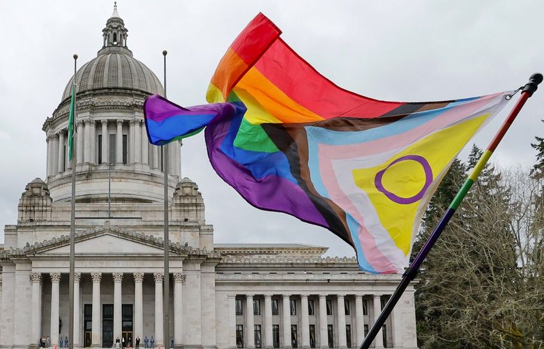 A supporter of trans rights waves a flag in front of the Temple of Justice as an opposing rally for opponents of legislation to exempt youth shelters from contacting parents of kids seeking gender affirming health care gathers on the steps of the Capitol Building Friday, April 21, 2023 in Olympia, Wash. 223644 223644
