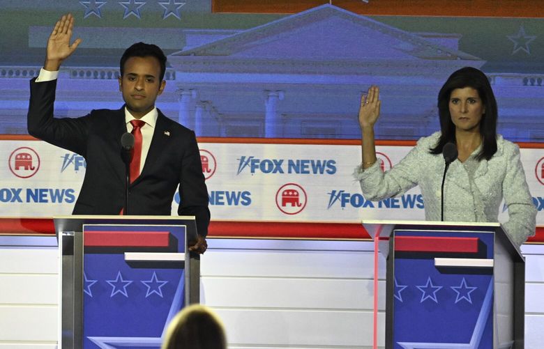 Entrepreneur Vivek Ramaswamy and former South Carolina governor Nikki Haley raise their hands during the GOP debate hosted by Fox News in Milwaukee on Wednesday. MUST CREDIT: Washington Post photo by Joshua Lott
