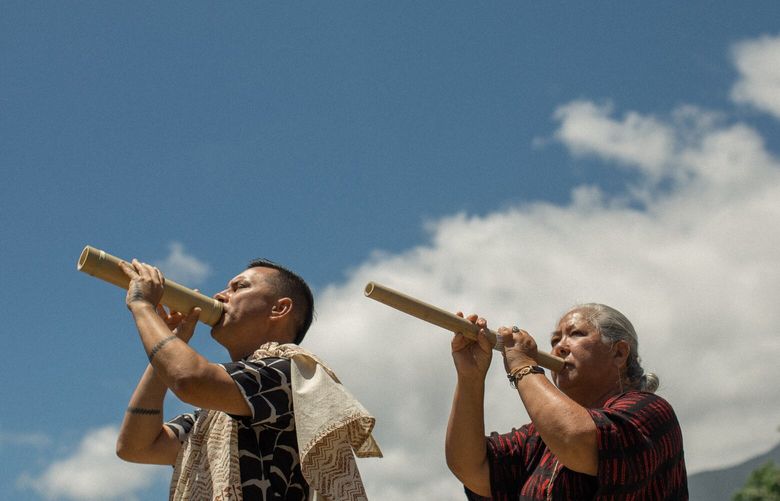 Cody Pueo Pata and Lori Lei Ishikawa blow into pu ?ohe, or hollowed-out bamboo pipes, during a traditional Hawaiian ceremony called a hula, on the island of Maui, Aug. 22, 2023. After Hawaii’s deadliest fires in more than a century, traditional ceremonies like a hula are addressing what many residents say is critical: spiritual healing. (Daeja Fallas/The New York Times) XNYT0242 XNYT0242