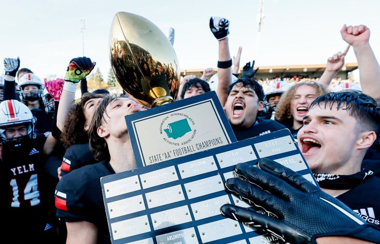 Yelm players celebrate with the trophy after a 20-13 win over Eastside Catholic for the 3A state championship Saturday. 222300
