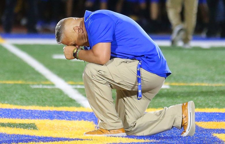 Bremerton football assistant coach Joe Kennedy takes a knee and prays at the 50-yard line after Bremerton’s 27-12 win over Mount Douglas at Bremerton Memorial Stadium in Bremerton, Wash. on Friday, Sept. 1, 2023.