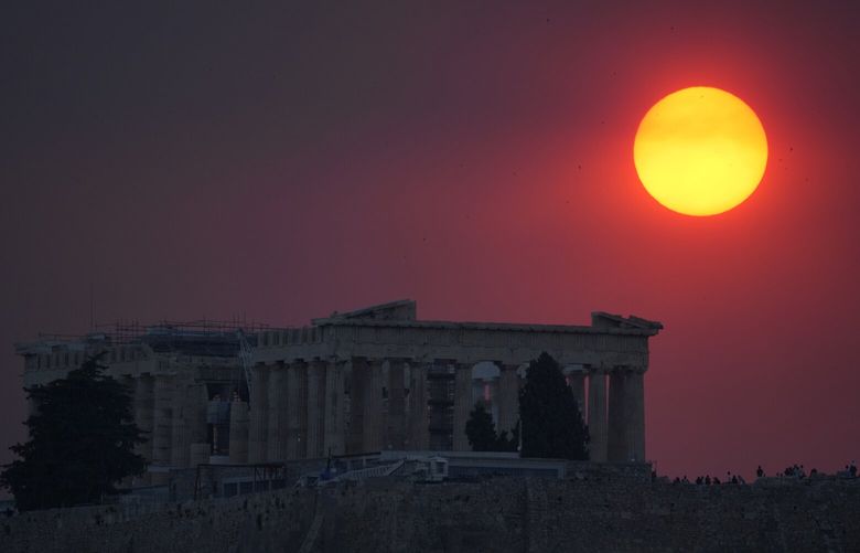 Smoke from a wildfire in the outskirts of the Greek capital covers the sun as it sets over the Parthenon temple atop of the ancient Acropolis ancient in Athens, Tuesday, Aug. 22, 2023. (AP Photo/Thanassis Stavrakis) POW108 POW108