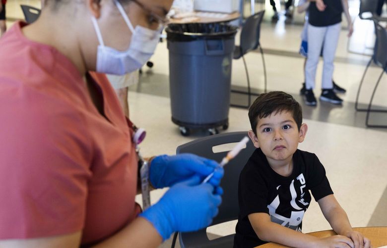 Pedro Barbosa, 6, right, looks at his vaccine shot at a vaccination clinic at Auburn Senior High School on July 14, 2023.