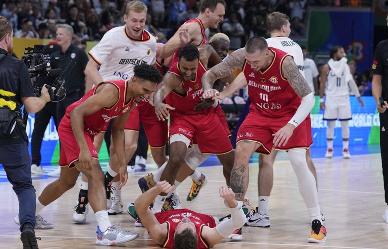 Germany guard Andreas Obst lays on the ground as teammates celebrates after winning against the United States in a Basketball World Cup semi final game in Manila, Philippines, Friday, Sept. 8, 2023. (AP Photo/Michael Conroy) XRR252 XRR252