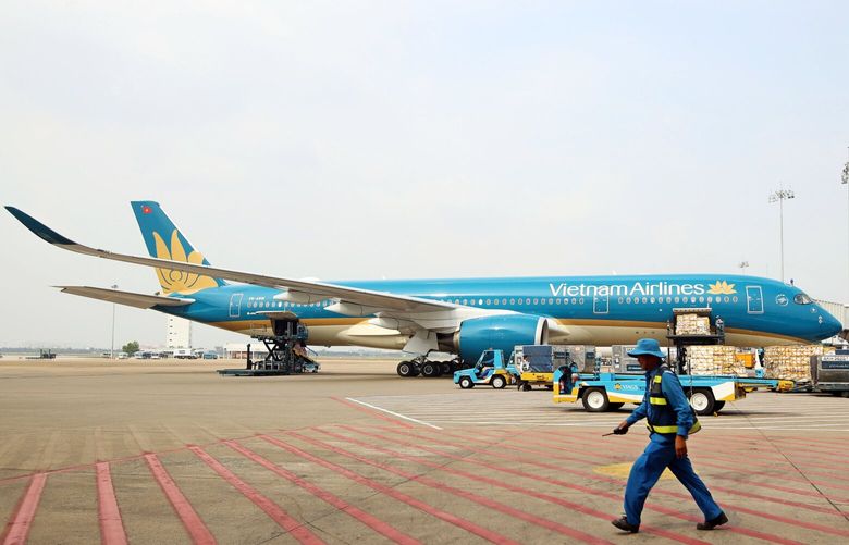 A member of the ground crew walks past a Vietnam Airlines JSC aircraft siting on the tarmac at Tan Son Nhat International Airport in Ho Chi Minh City, Vietnam, on Wednesday, Jan. 11, 2017. The Vietnamese economy expanded more than 6 percent last year and is set to be among the world’s best performers over the next two years with growth rates exceeding 6 percent, according to the World Bank. 693417671