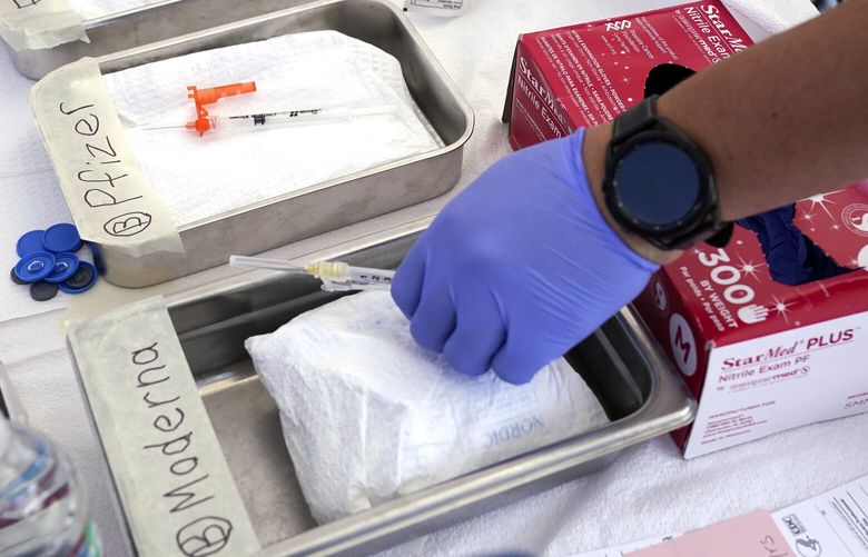 FILE – Syringes with vaccines are prepared at the L.A. Care and Blue Shield of California Promise Health Plans’ Community Resource Center where they were offering members and the public free flu and COVID-19 vaccines Oct. 28, 2022, in Lynwood, Calif. Updated COVID-19 vaccines are expected in the latter half of 2023 — just in time to pair them with flu shots. (AP Photo/Mark J. Terrill, File) NY575 NY575