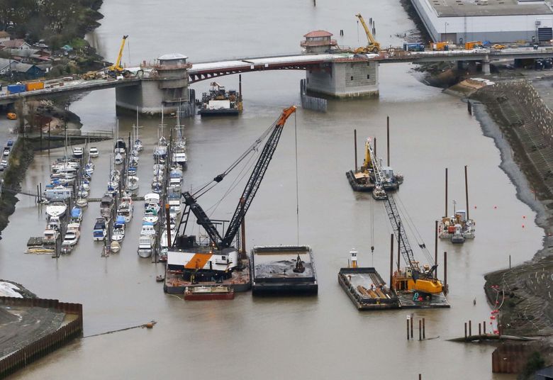 Next to the South Park Bridge, polluted soil is scooped from the Duwamish River in 2014. This dredging was a precursor to Superfund cleanup. (Alan Berner / The Seattle Times, 2014)