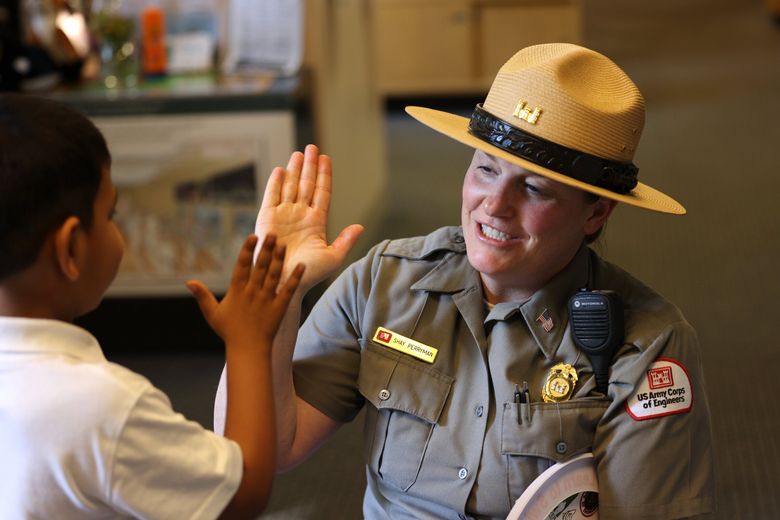 Shay Perryman, supervisory natural resource specialist with the U.S. Army Corps of Engineers, gives a high-five to Shereyaan Gupta, age 5, from Redmond. Perryman is an interpreter and park ranger. “We just try to make a connection,&#8221; she says. &#8220;What is going to make you really interested in taking care of the environment and green spaces around you? Especially for kids, it is important on how to stay safe in the water, such as life jackets. We can provide that education, even though you can’t swim here.” (Karen Ducey / The Seattle Times)