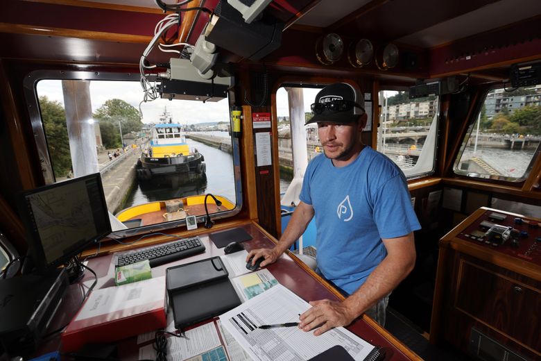 Wade Rasmussen, captain of the Ocean Titan, a tugboat owned by Western Towboat Company, works on his voyage plan while tied up in the large lock at the Ballard Locks. The boat was headed to nine ports in southeast Alaska, moving freight from port to port. Rasmussen was figuring his plan up the Inside Passage, using electronic chart systems. Behind is the tugboat Arctic Titan. (Karen Ducey / The Seattle Times)