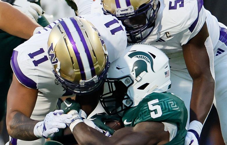 Washington Huskies linebackers Alphonzo Tuputala, left, and Edefuan Ulofoshio combine to take down Michigan State Spartans running back Nathan Carter in the backfield during the third quarter Saturday, Sept. 16, 2023 in East Lansing, MI. 224978