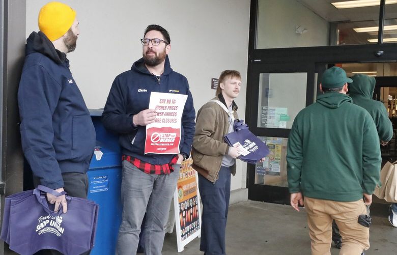 Union members of UFCW 3000 gather to pass out free tote bags to shoppers at the Holman Road NW QFC, April 6, 2023. From left, Daniel Cobb, Chris Crawford an Nile Bentley.