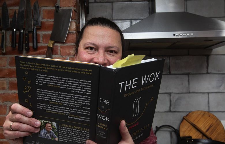 J. Kenji López-Alt, with his personal copy of his book “The Wok,” inside his kitchen, Monday, Dec. 12, 2022 in Seattle. López-Alt makes the “My Mom’s Japanese-Style Mapo Tofu” recipe from the book.