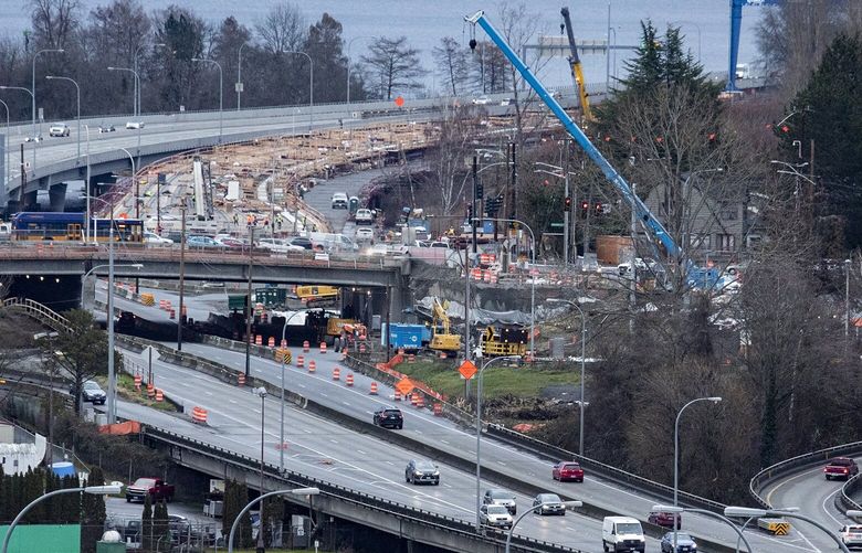 The Highway 520 megaproject, about two-thirds completed, is seen in the background where the Montlake lid is under construction, Thursday, Jan. 20, 2022 in Seattle. In the foreground is the Portage Bay Bridge which is to be replaced next, but a funding ìpotholeî needs to be filled and Gov. Jay Inslee proposes to spend $406 million, including some COVID-19 economic relief money. 219373