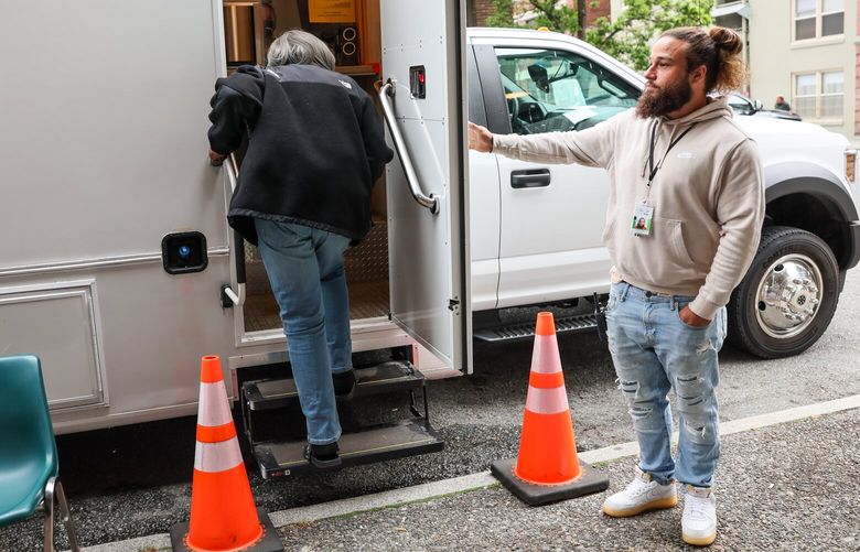 Brendan Medbury, hospitality and engagement worker with Evergreen Treatment Services, holds the door for a client Friday morning in the Belltown neighborhood of Seattle, Washington on August 18, 2023.
