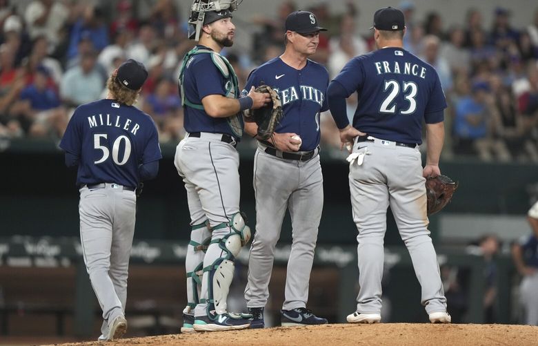 Seattle Mariners manager Scott Servais (9) stands on the mound with first baseman Ty France (23) and catcher Cal Raleigh (29) as starting pitcher Bryce Miller (50) leaves during the fifth inning of the team’s baseball game against the Texas Rangers in Arlington, Texas, Friday, Sept. 22, 2023. (AP Photo/LM Otero)