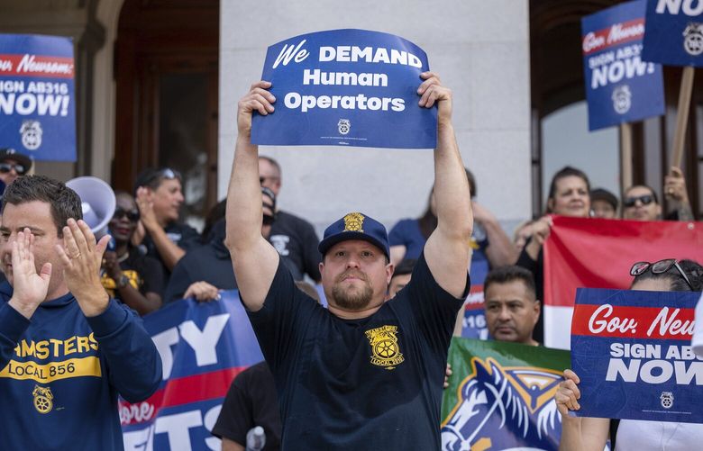 Teamsters union members hold signs urging Gov. Gavin Newsom to sign Assembly Bill 316, which would require in-person human supervision of self-driving vehicles weighing over 10,000 pounds, at the state Capitol in Sacramento, Calif., on Tuesday, Sept. 19, 2023. California lawmakers, union leaders and truck drivers are trying to steer Democratic Gov. Gavin Newsom toward signing into law a proposal that could save jobs as self-driving trucks are tested for their safety on the roads. (Paul Kitagaki Jr./The Sacramento Bee via AP) CASAB201 CASAB201