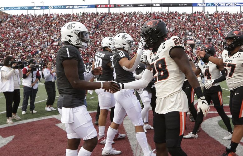 Washington State quarterback Cameron Ward (1), Oregon State defensive back Kitan Oladapo (28) and other members of their teams greet each other during the coin toss before an NCAA college football game, Saturday, Sept. 23, 2023, in Pullman, Wash. (AP Photo/Young Kwak)