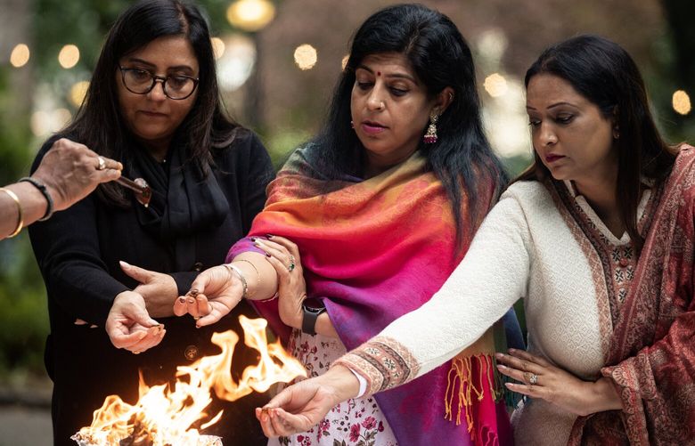 Priest Pandit Srinivasa pours oil into the fire as, from left, Seema Sharma, Nidhi Mehta and Vasudha Sharma place offerings into the flames during the Shanti Puja for Jaahnavi Kandula Sunday, Sept. 24, 2023, at Denny Park in Seattle. A Shanti Puja is a Hindu ritual or prayer ceremony performed to invoke peace, harmony, and well-being. It is typically conducted during significant life events, such as after a person passes away like Jaahnavi Kandula.
