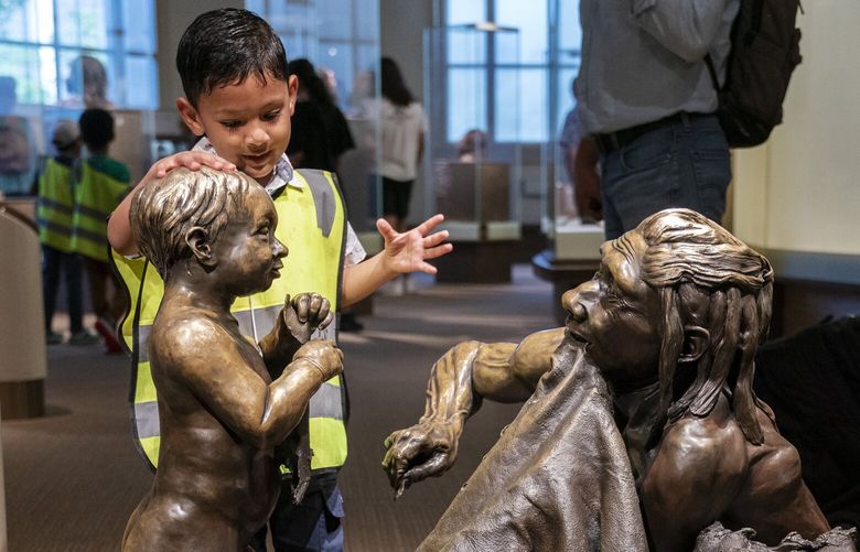A boy pats the head of a sculpture of a Neanderthal boy, inside the Smithsonian Hall of Human Origins, Thursday, July 20, 2023, at the Smithsonian Museum of Natural History in Washington. Using the new and rapidly improving ability to piece together fragments of ancient DNA, scientists are finding that traits inherited from our ancient cousins are still with us now, affecting our fertility, our immune systems, even how our bodies handled the COVID-19 virus. (AP Photo/Jacquelyn Martin) NY703 NY703