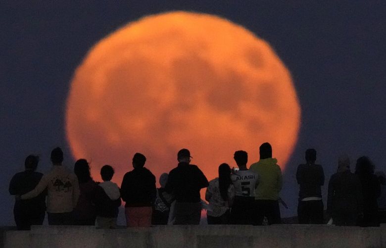 A rare Blue Supermoon rises over Lake Michigan as spectators watch from Chicago’s 31st Street beach Wednesday, Aug. 30, 2023. (AP Photo/Charles Rex Arbogast) ILCA101 ILCA101
